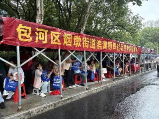 高考首日合肥大雨滂沱 社区为考生家长支起避雨长廊