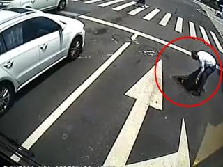 青岛一井盖移位成“马路陷阱” 驾驶员烈日下复位保障市民出行安全